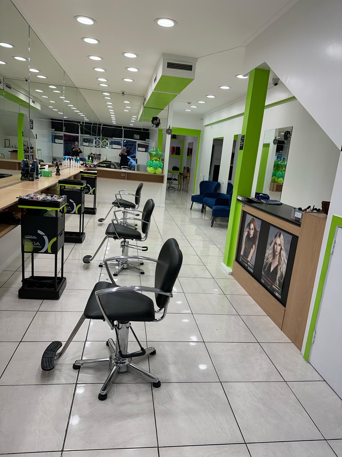 Inside the bright lime green and white salon, with styling chairs and mirrors